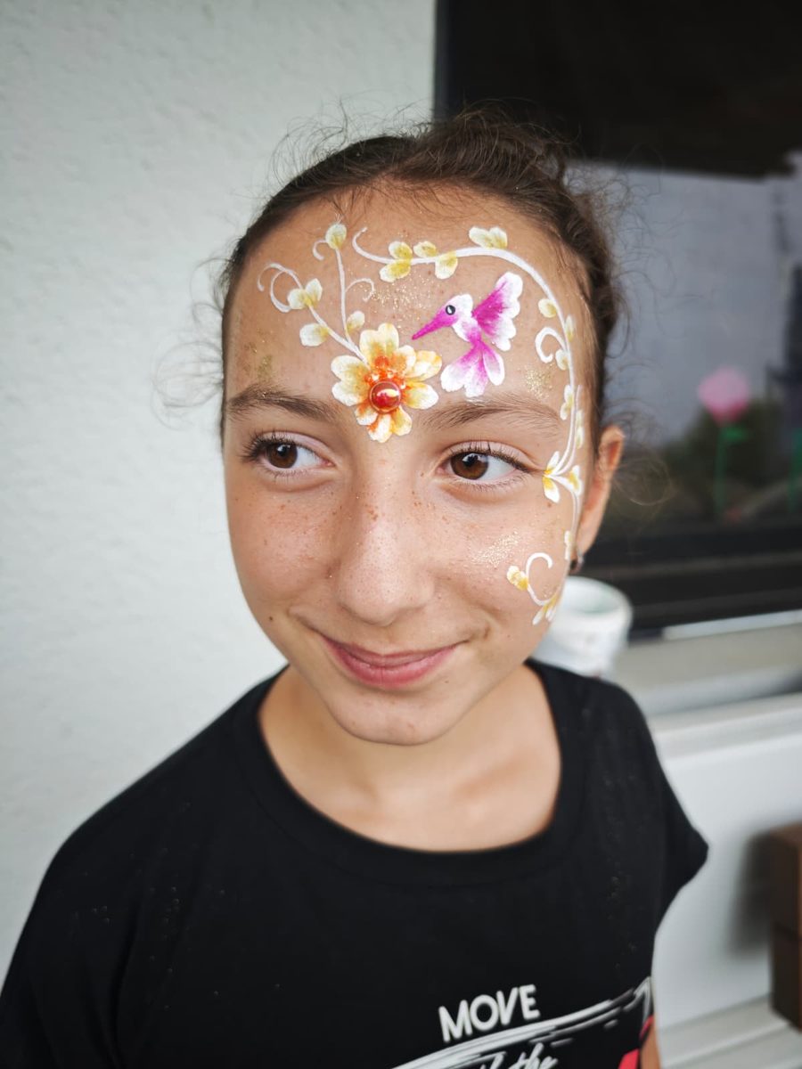 Kinderschminken: Kolibri mit Blumenranke und Glitzer