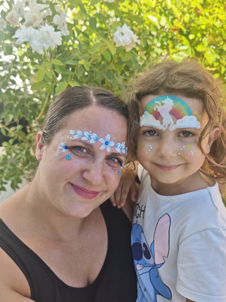 Stefanie mit geschminktem Kind: Blütenranke und Einhorn-Regenbogen